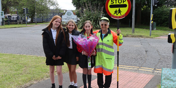 Three pupils give a large bunch of flowers to a school crossing patrol woman