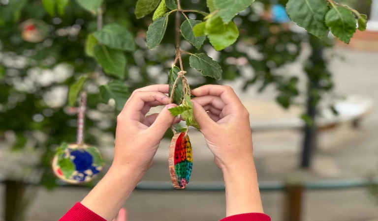 Child placing a wooden decoration on a tree with their memory design.
