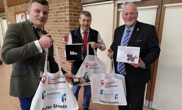 Three men holding tote bags containing security equipment