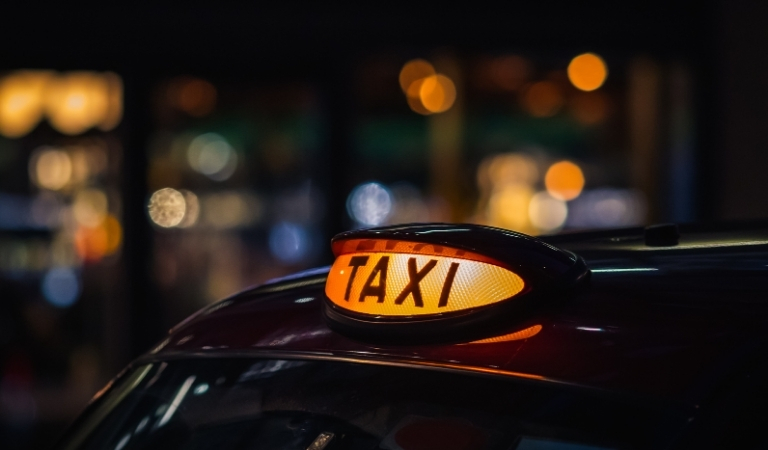 A black taxi sign illuminated at night time