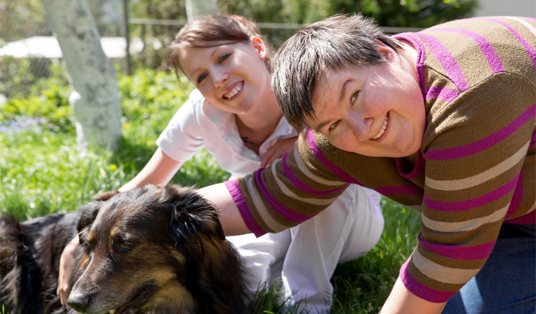 Photo of care worker and service user in a field.